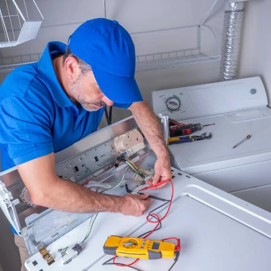 Technician testing top-loading washing machine electronics with a meter